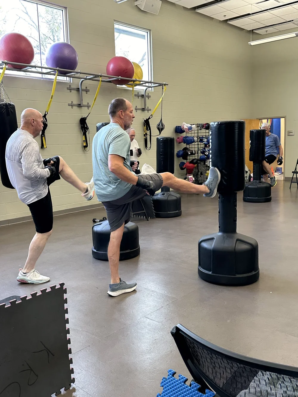 Members kicking heavy bags in class